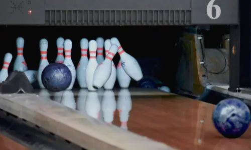 Des boules de bowling s'écrasent sur des quilles dans un bowling