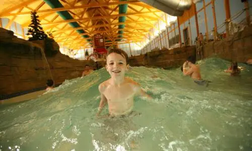 Garçon souriant dans une piscine à vagues.