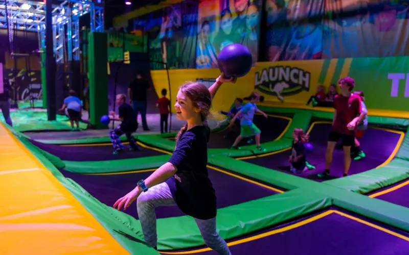 Une fille lançant une balle au prisonnier dans un parc de trampolines intérieur