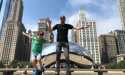 Père et fils sautant devant The Bean