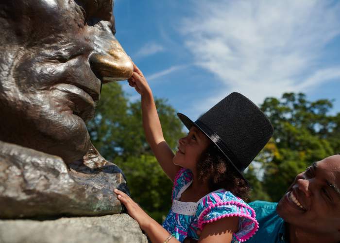 Un père soulève sa fille pour toucher le nez de la statue de Lincoln.