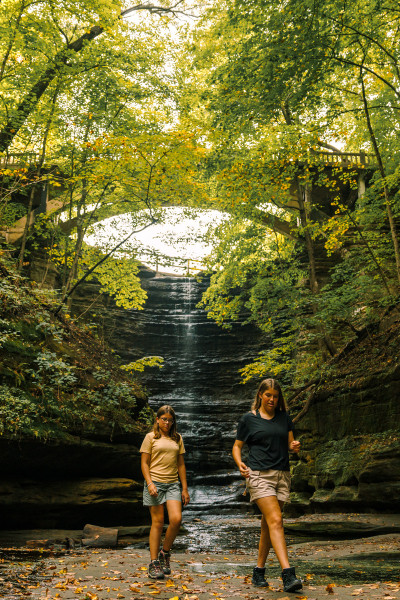 Deux jeunes filles marchent devant une cascade dans le parc d'État de Matthiessen.