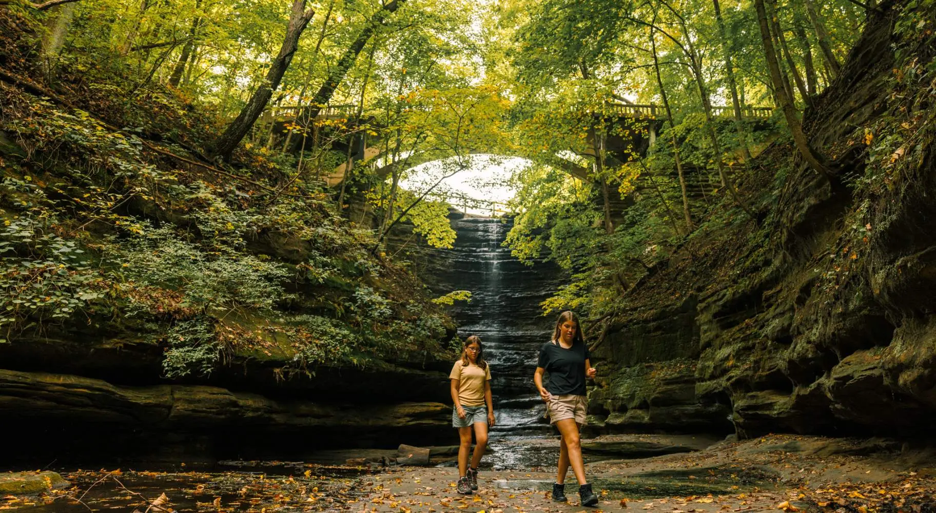 Deux jeunes filles marchent devant une cascade dans le parc d'État de Matthiessen.