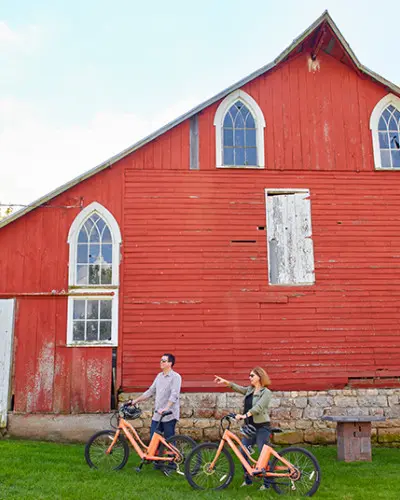 Un couple à vélo devant une grange rouge