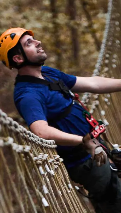 Des grimpeurs harnachés traversent un pont.