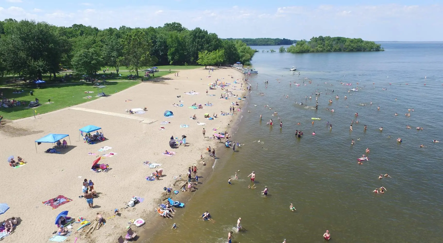Vue aérienne d'une plage avec des personnes profitant du soleil, du sable et de l'eau.