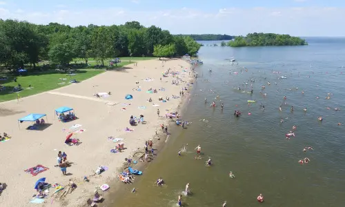 Vue aérienne d'une plage avec des personnes profitant du soleil, du sable et de l'eau.