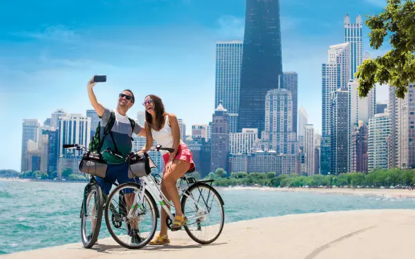Un couple fait du vélo sur le sentier au bord du lac et prend une photo