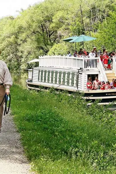 Une femme promène son cheval le long du canal au passage du bateau du canal I&M.