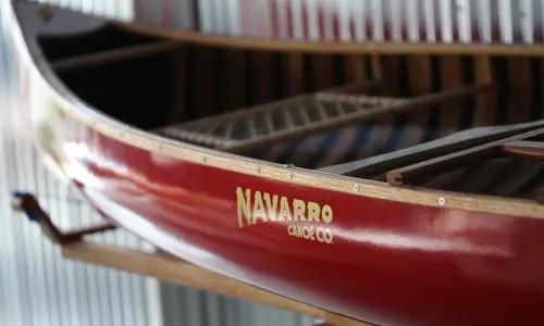 Un canoë rouge avec le logo Navarro Canoe.