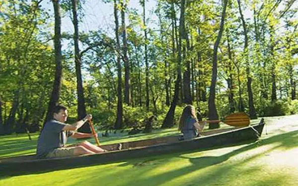 Image latérale d'un père et d'une fille descendant en canoë une rivière marécageuse.