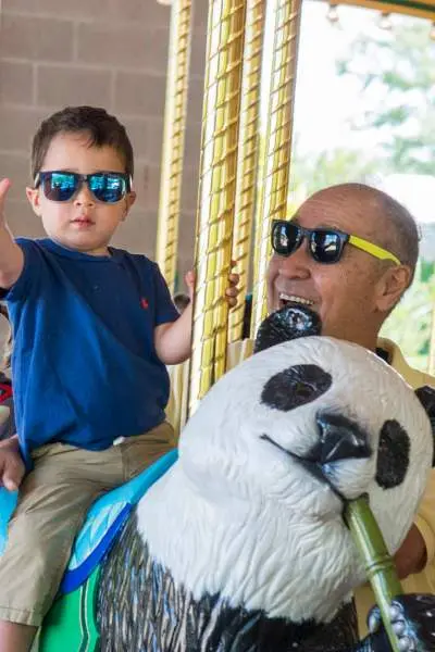 Un enfant en bas âge et ses grands-parents sur le carrousel du zoo de Brookfield.