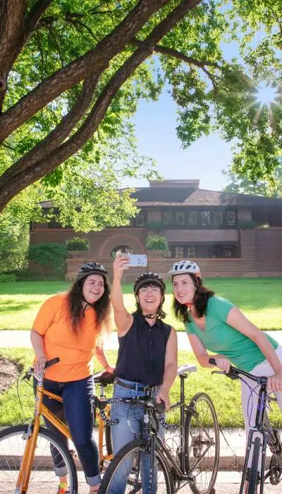 Personnes à vélo posant pour une photo avec une maison en arrière-plan