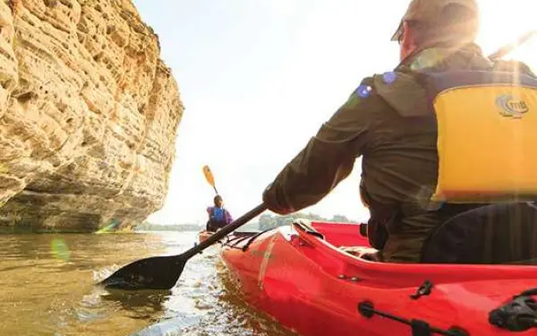 Un homme dans un kayak rouge pagayant autour d'une formation rocheuse