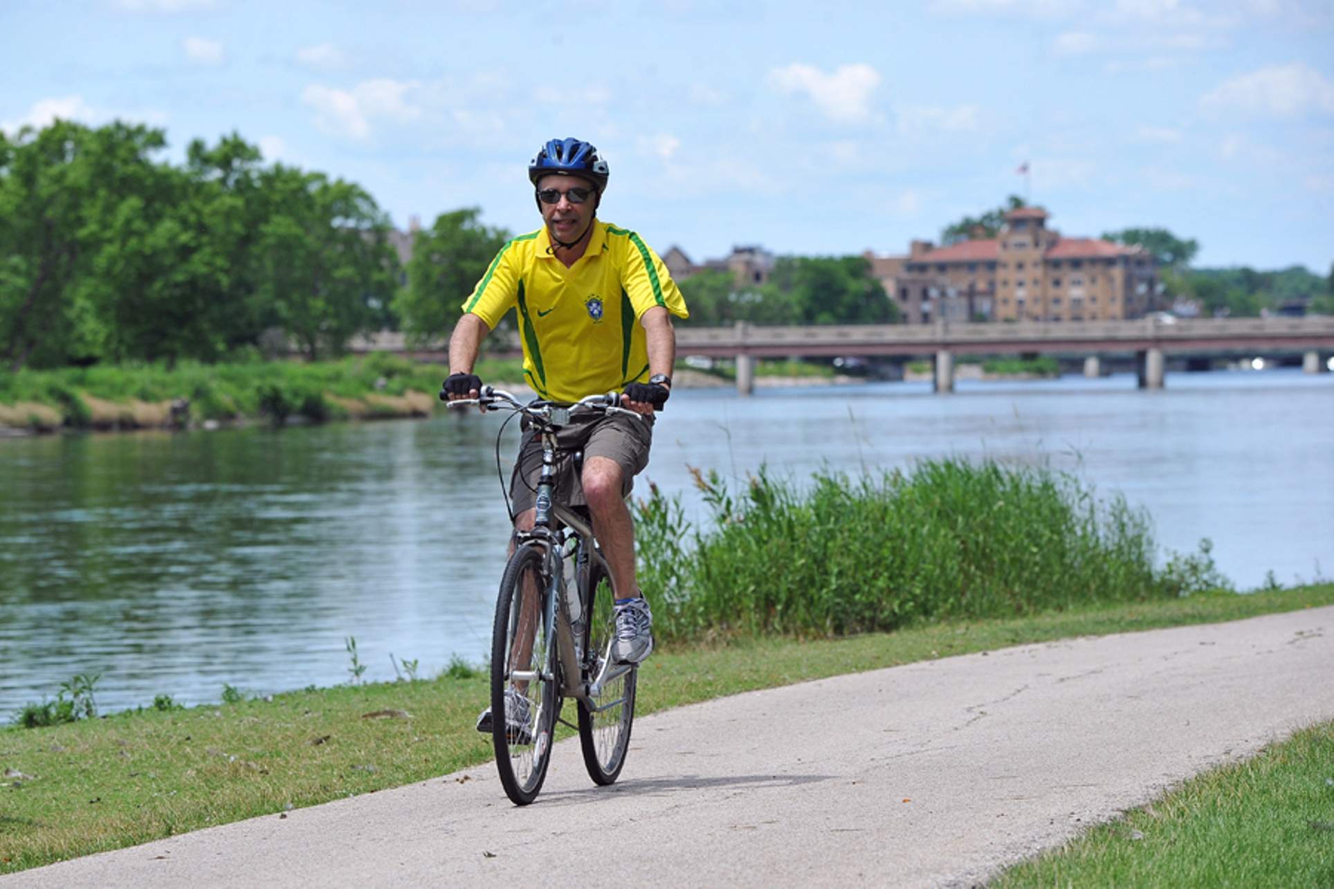 Un homme vêtu d'une chemise jaune vif fait du vélo sur un sentier près de la rivière Fox.