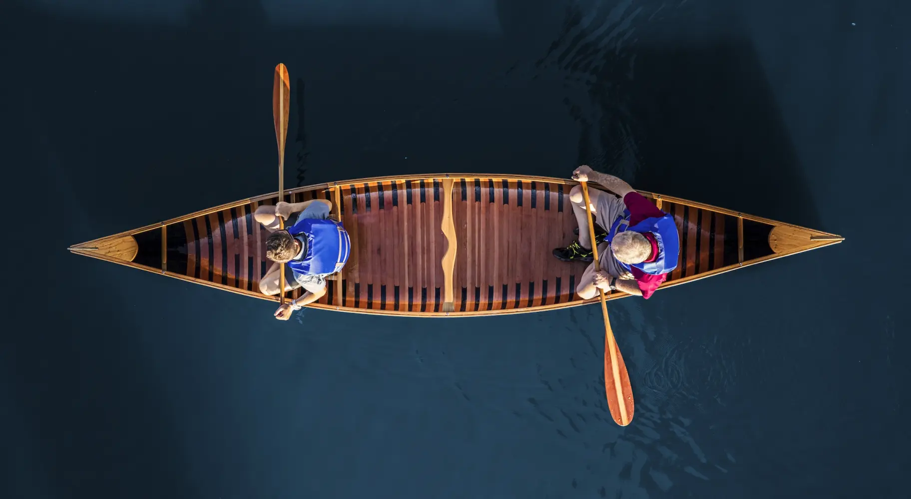 Photo aérienne de deux personnes dans un canoë sur de l'eau bleue