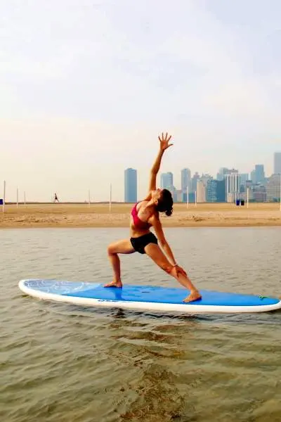 Femme s'étirant sur une planche à pagaie sur un lac