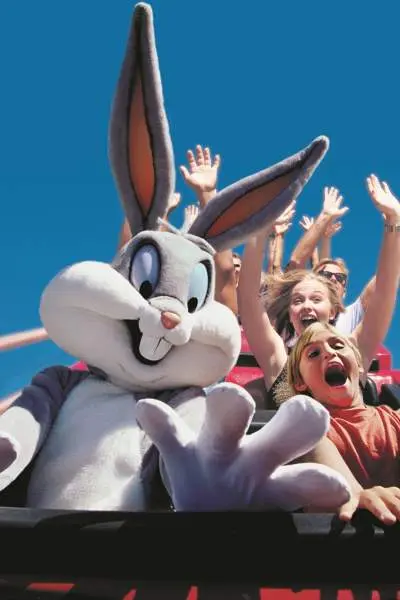 Des enfants sur des montagnes russes avec une personne déguisée en Bugs Bunny