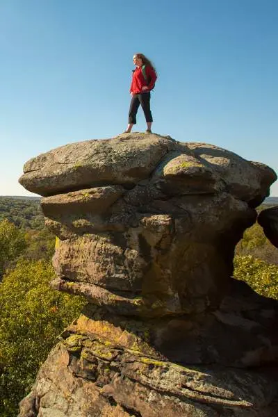 Femme debout sur un grand rocher surplombant la forêt en contrebas