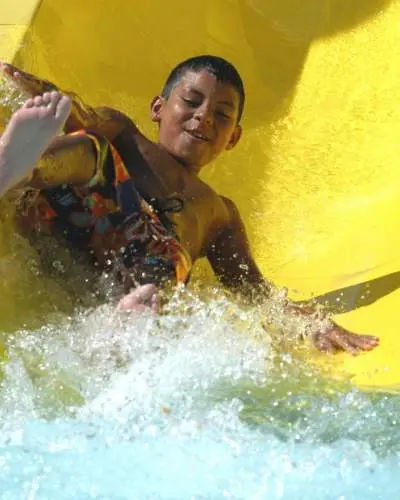 Enfant descendant du toboggan aquatique jaune Great America Hurricane Harbor