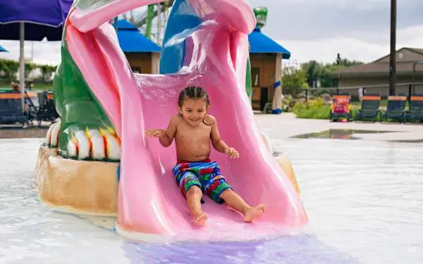Un enfant glisse sur un petit toboggan dans un parc aquatique.