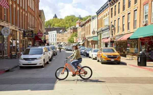 Un cycliste sur un vélo électrique traverse la rue principale d'une petite ville.