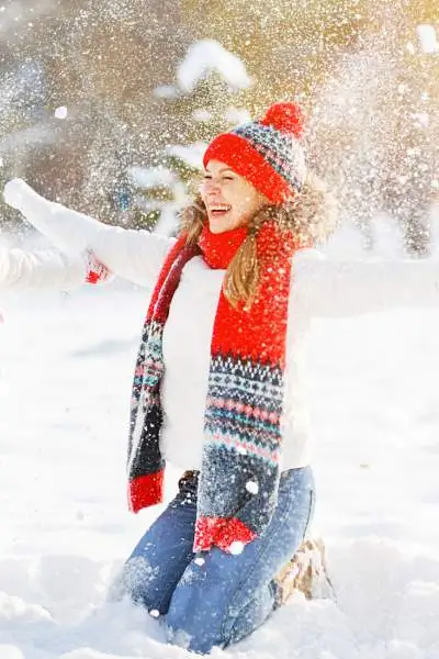 Une mère et son enfant habillés chaudement pour le temps et jetant de la neige en l'air.