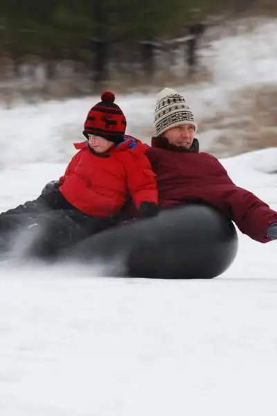 Un homme et un garçon font du snowtubing sur le Mont Hoy