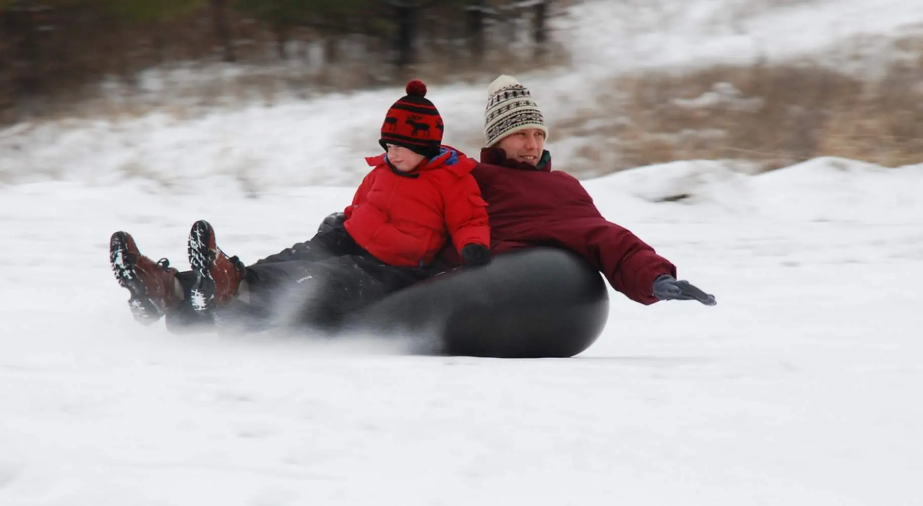Un homme et un garçon font de la glissade sur tube sur le Mont Hoy