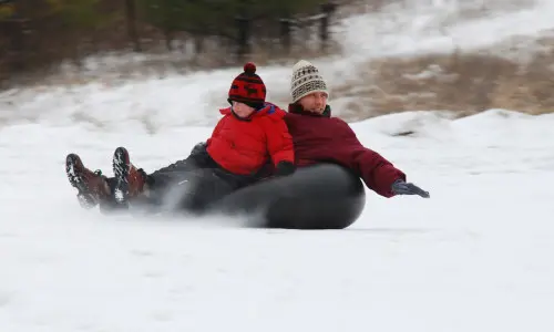 Un homme et un garçon font de la glissade sur tube sur le Mont Hoy