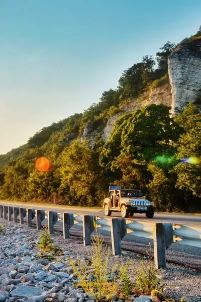 Le soleil se lève sur l'eau et une voiture roule sur la route à côté.