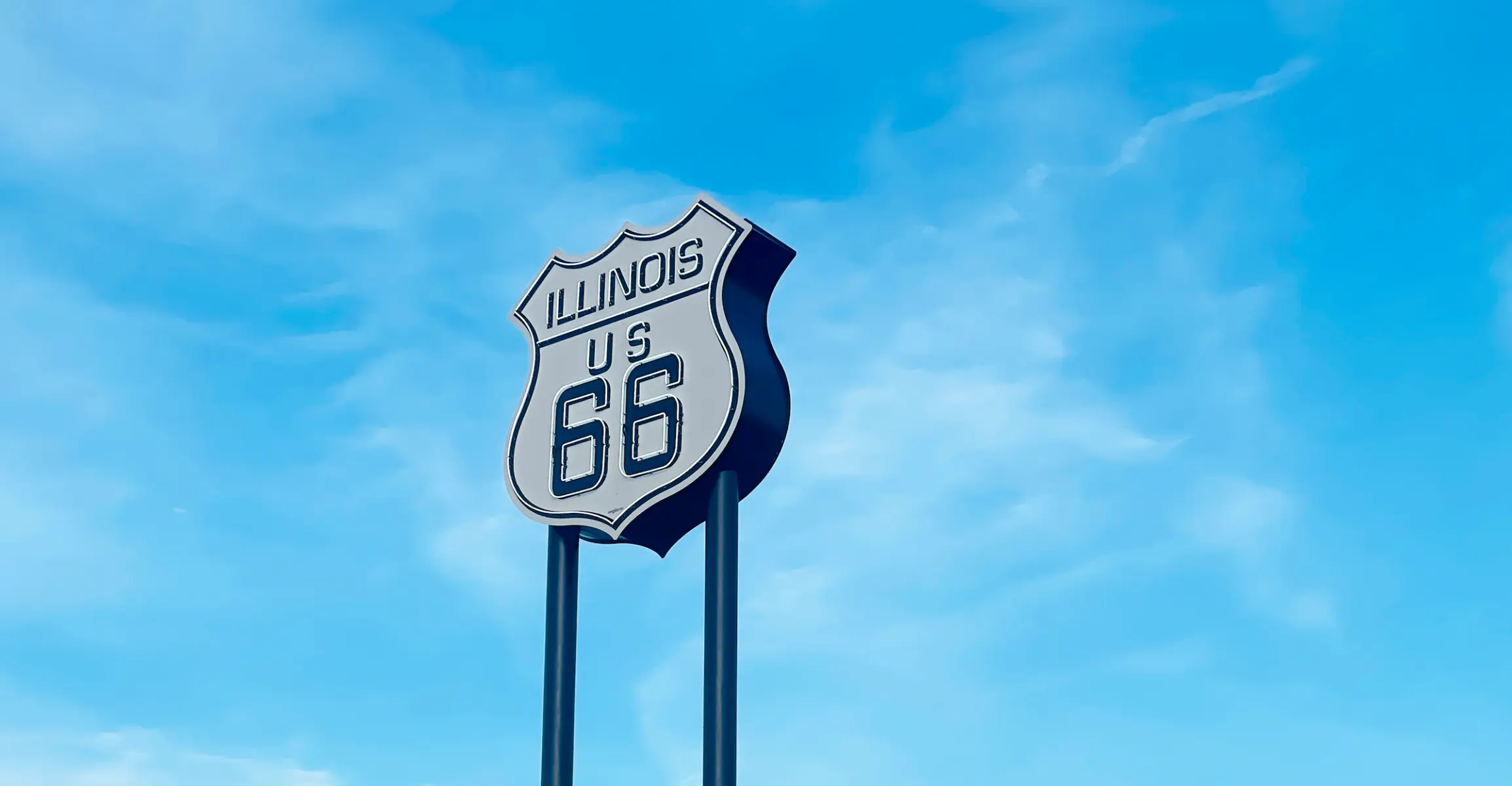 Un panneau lumineux Route 66 sur deux poteaux contre un ciel bleu