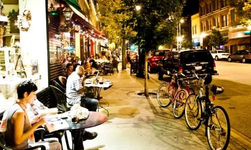 Personnes lisant et mangeant à l'extérieur des magasins le long de la rue