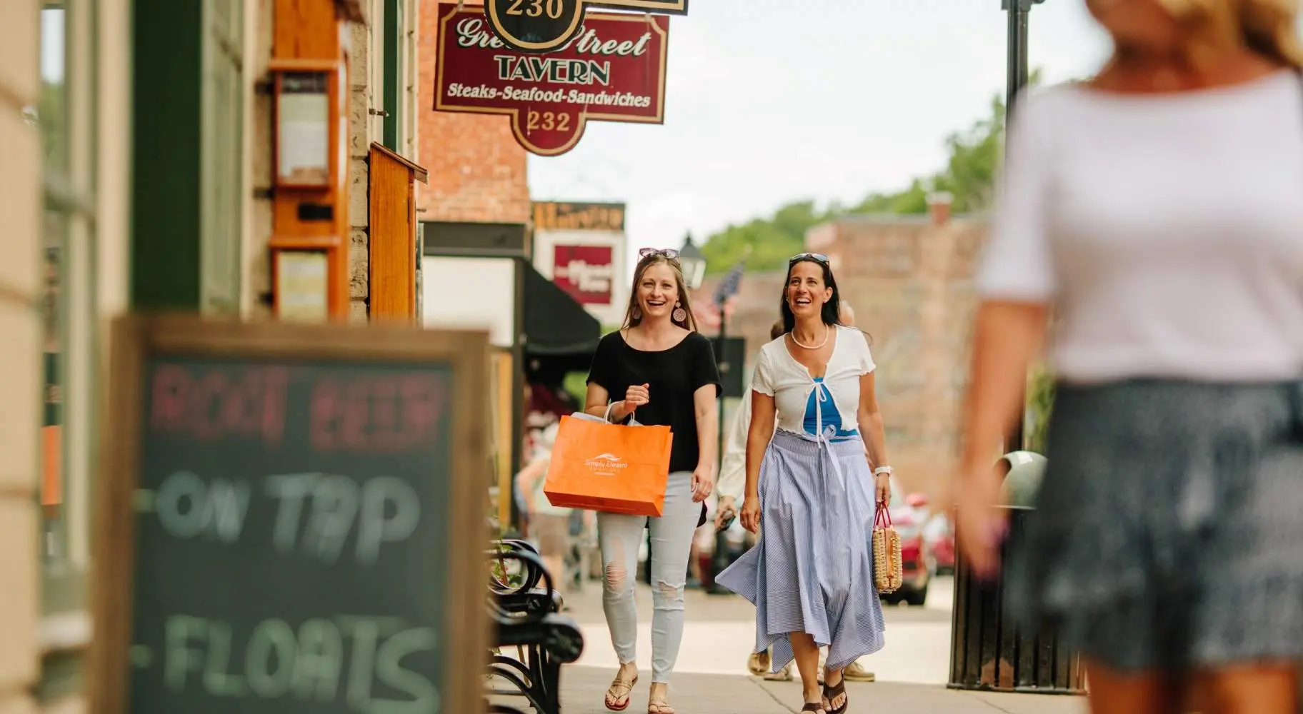 Deux femmes marchant dans la rue principale de Galena, l'une portant un sac à provisions orange.