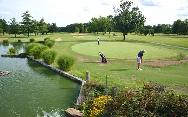 Golfeurs jouant une partie sur un green, à côté d'un plan d'eau