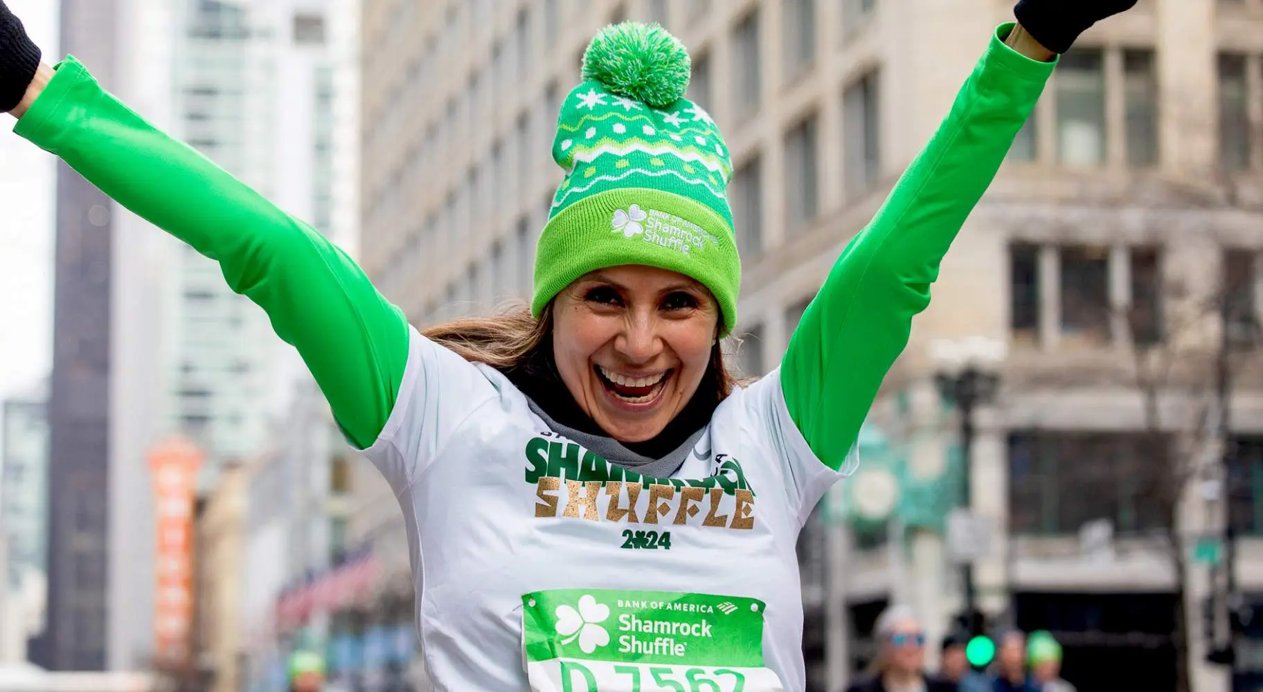 Une participante à une course à pied en vert, les bras levés en l'air