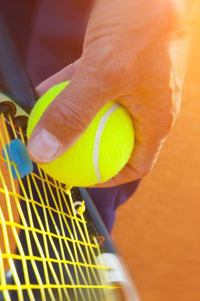 Gros plan sur une personne qui s'apprête à servir une balle de tennis.