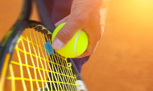 Gros plan sur une personne qui s'apprête à servir une balle de tennis.