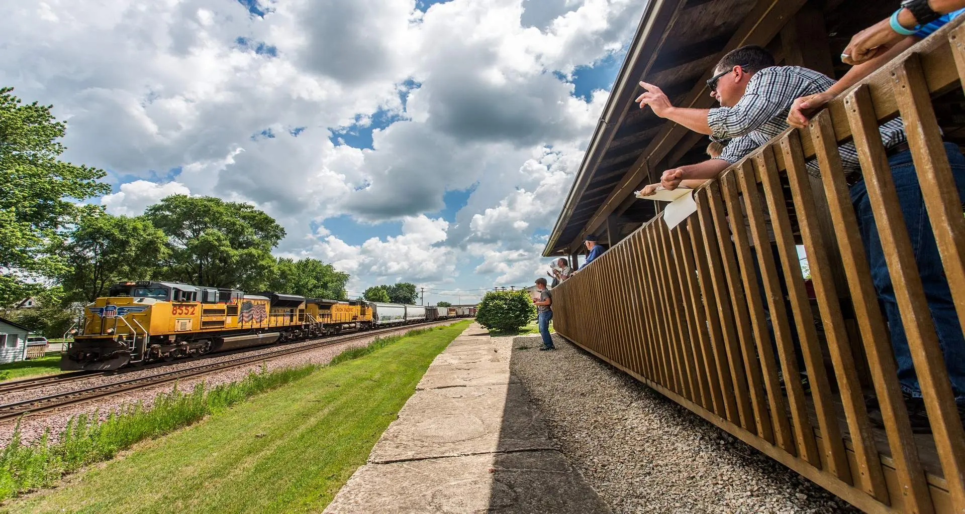 Personnes regardant passer un train dans un parc ferroviaire