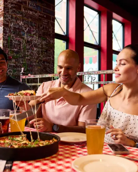 Des amis qui partagent une pizza et des boissons au restaurant.